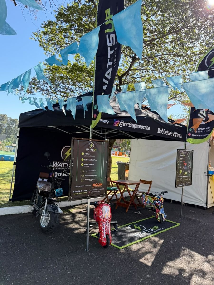 Estande da WattsUp com banner dos produtos e scooter X13
